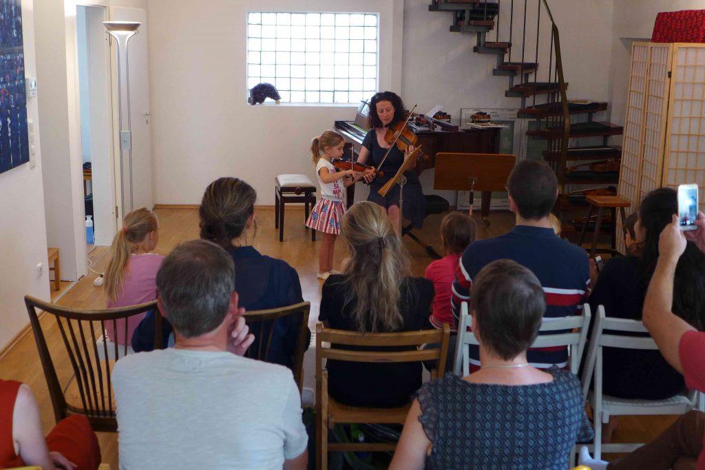 Mädchen spielt Geige im Konzert zusammen mit einer erwachsenen Geigerin